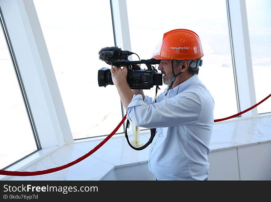 Person in Blue Dress Shirt Holding Black Professional Vidreo Camera