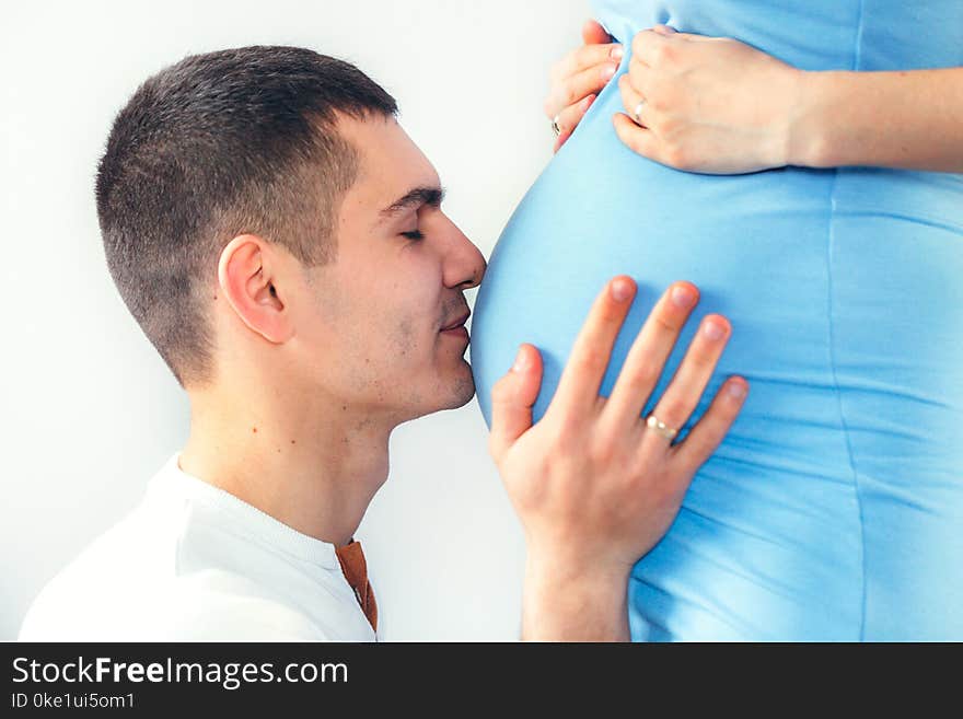 Close up of a men kissing the belly of his lovely pregnant wife standing in the bedroom. Close up of a men kissing the belly of his lovely pregnant wife standing in the bedroom