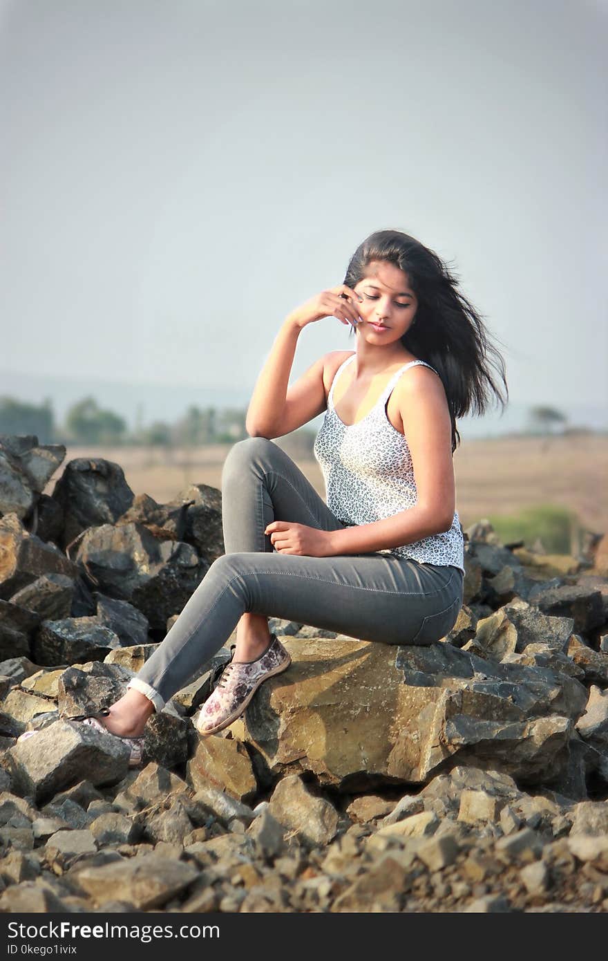 Woman Wearing White Tank Top Sitting on Rock