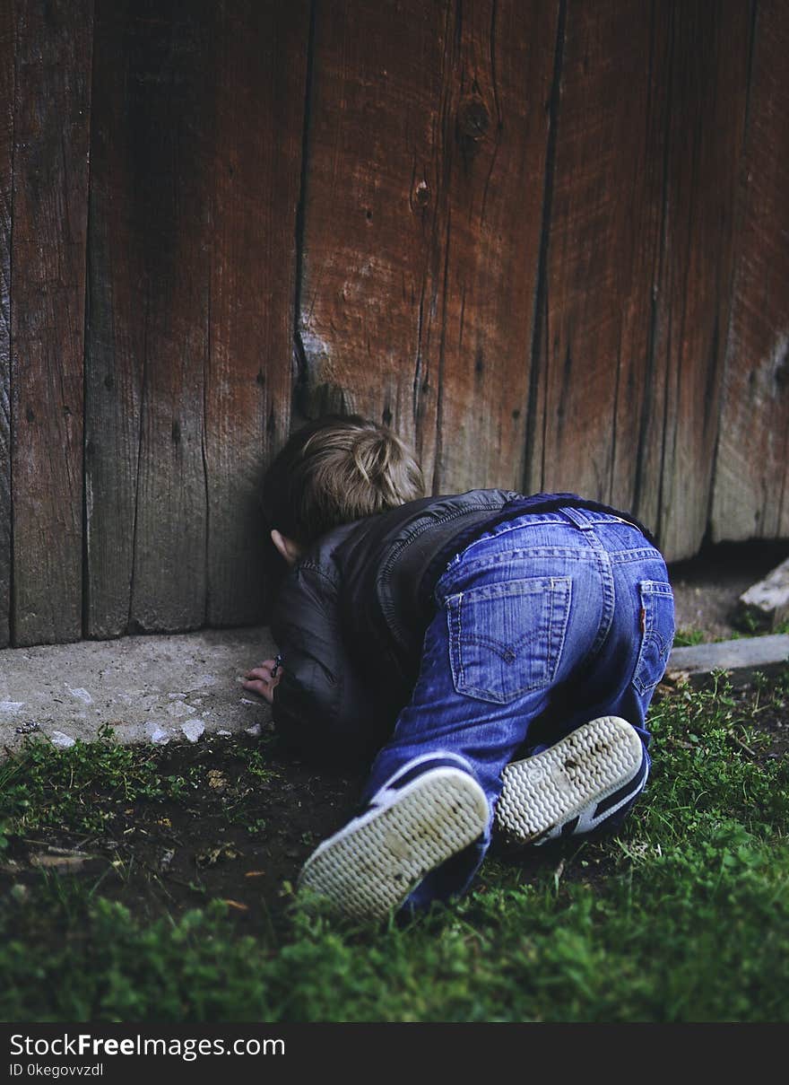 Photo of Boy Peeking on Brown Wooden Fence