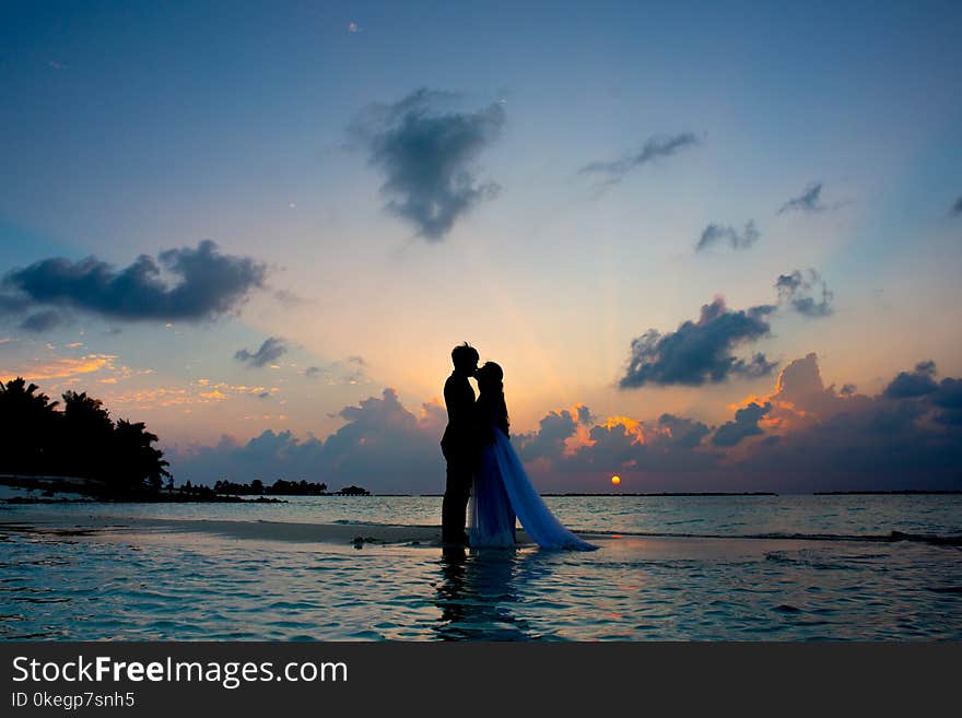 Silhouette Photo of Man and Woman Kisses Between Body of Water