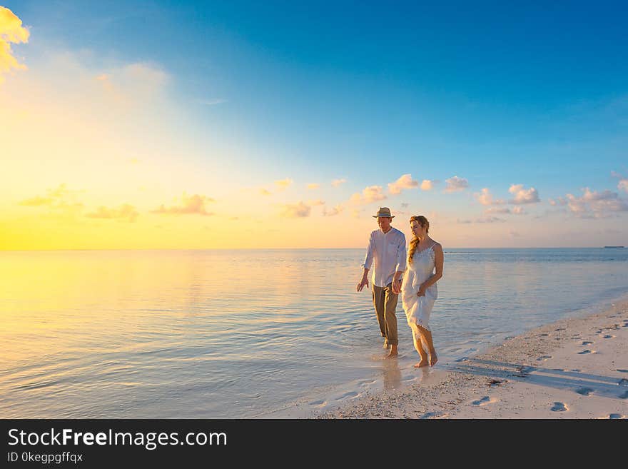 Couple Walking on Seashore Wearing White Tops during Sunset