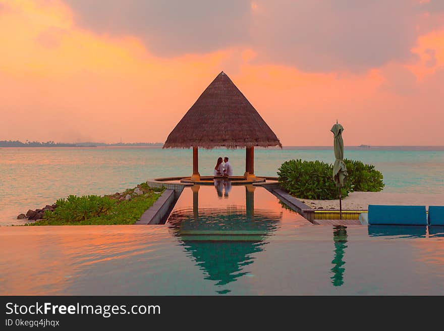 Couple Under Hut Beside Sea and Infinity Pool