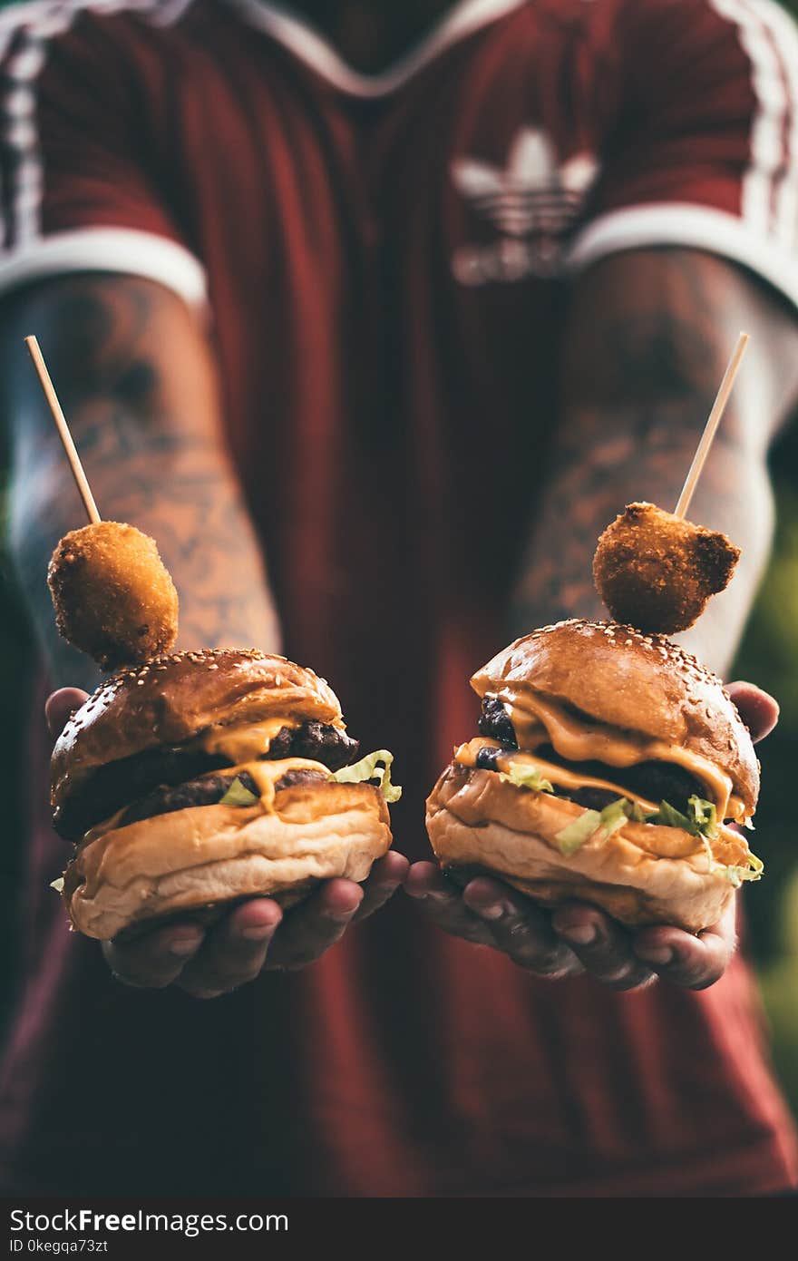 Person Holding Two Hamburgers