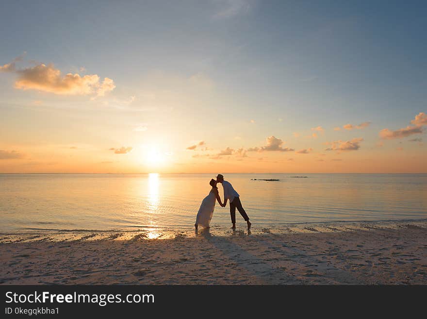 Man and Woman Standing on Shore Kissing