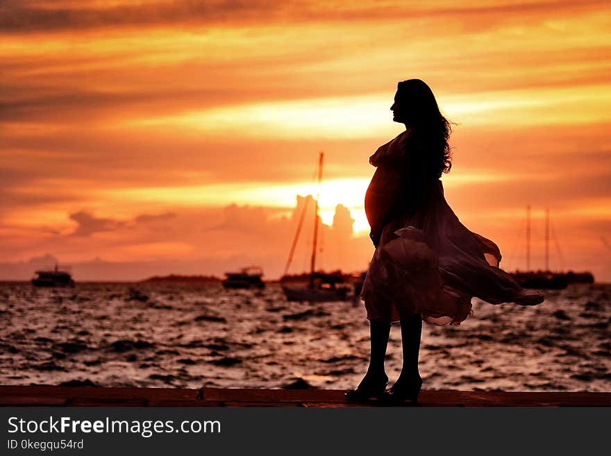 Pregnant Woman Standing Near Seashore during Sunset