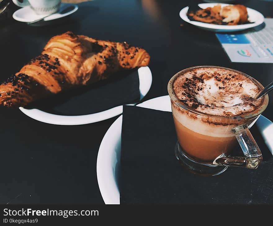 Clear Glass Cup Filled With Cappuccino Beside Croissant Bread