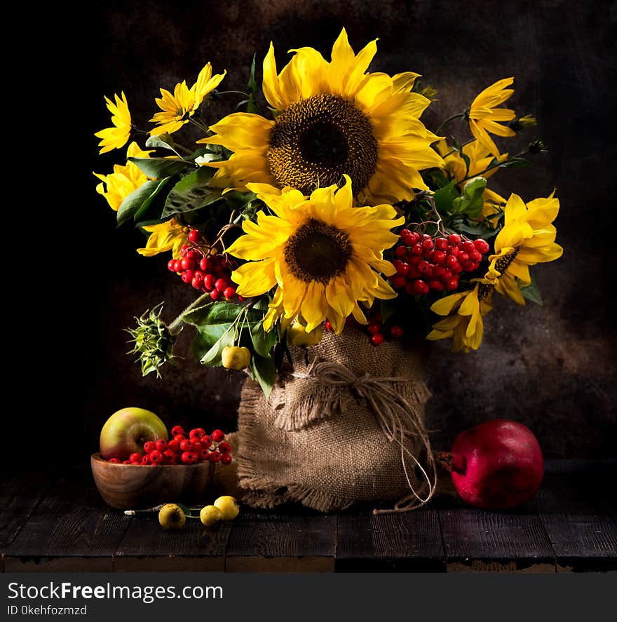 Still life bouquet of sunflowers in a vase, yellow autumn flowers, fruits and berries
