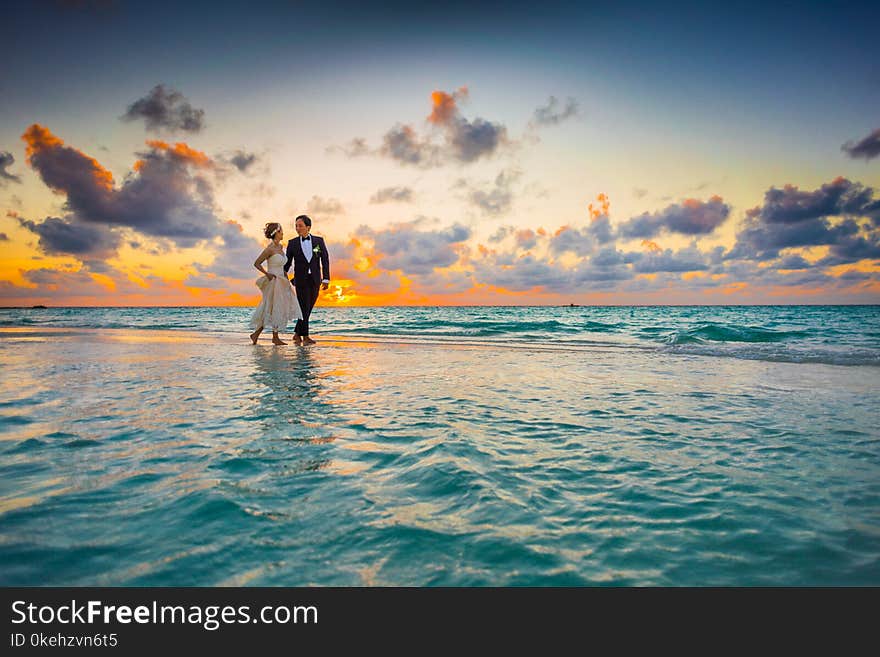 Man and Woman Walking of Body of Water