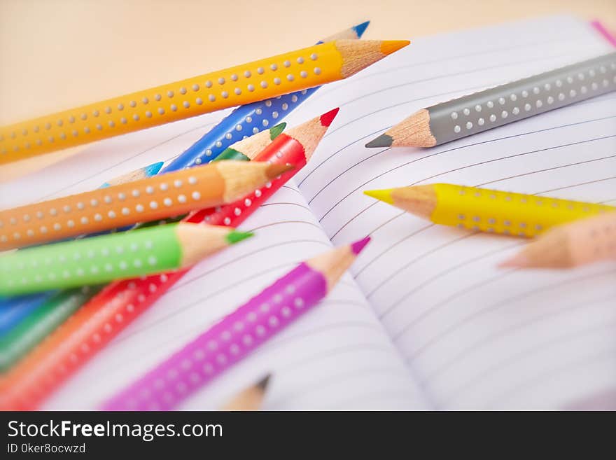 Open notebook and colorful pencils on table.