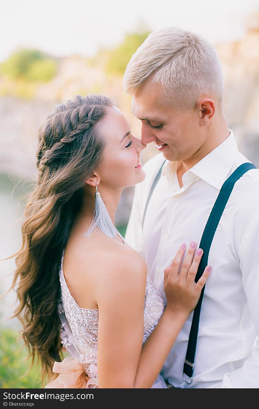 Elegant curly bride and groom outdoors on the background the lake