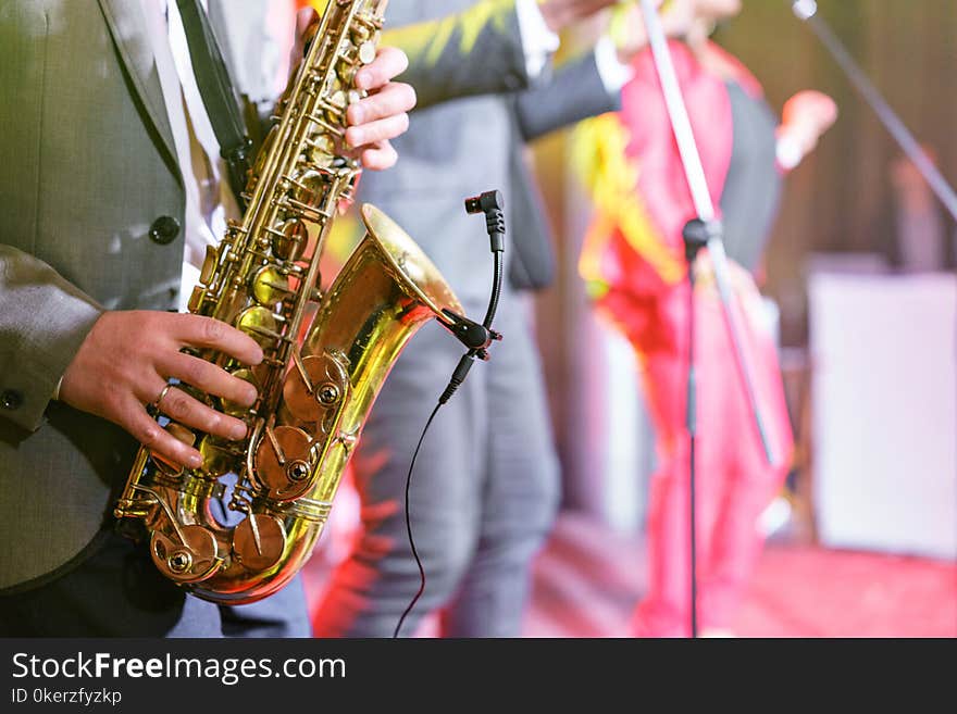 A young man in a suit playing on saxophone. Elegant saxophonist plays jazz. close-up musical instrument, sax in the