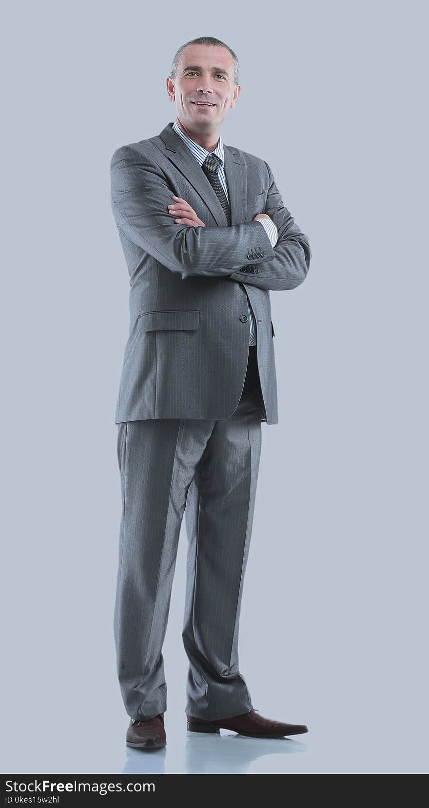 Mature business man arms folded on gray.