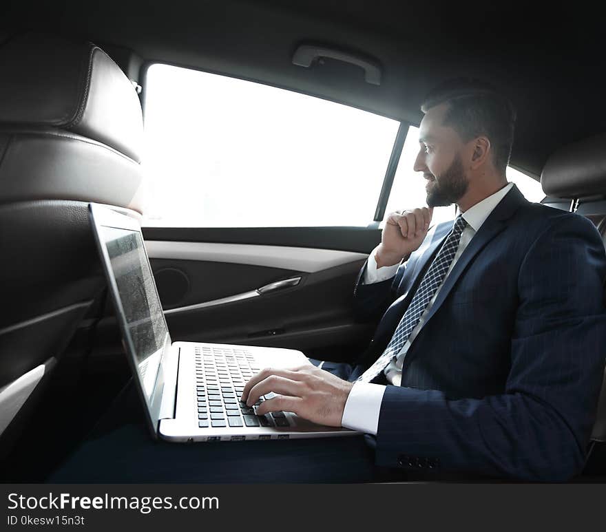 Businessman typing text on laptop while sitting in car