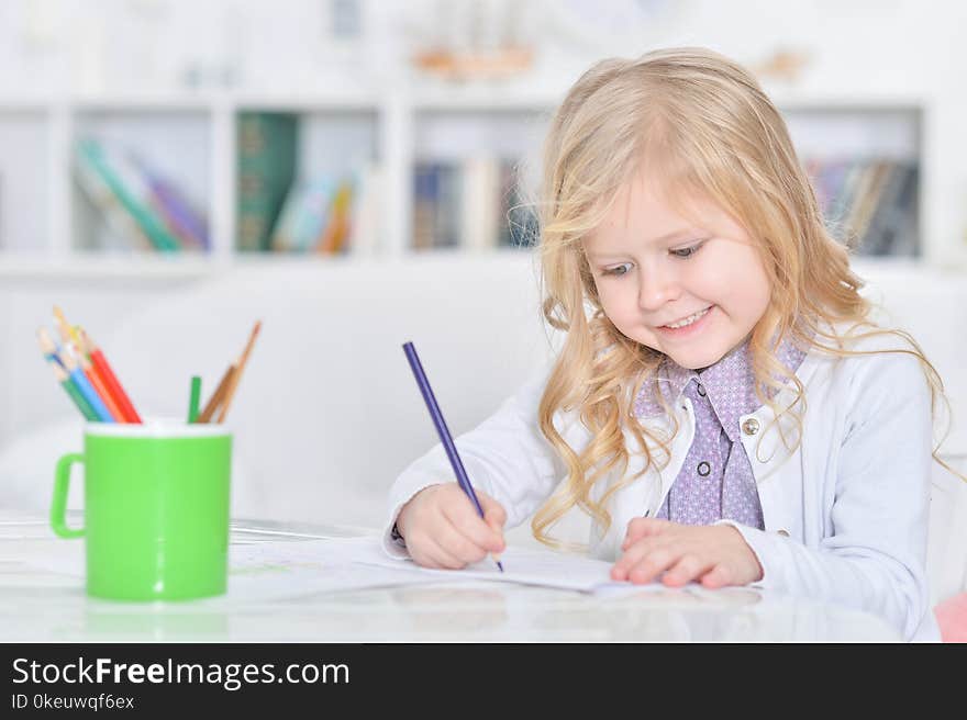 Portrait of cute little girl drawing with pencils