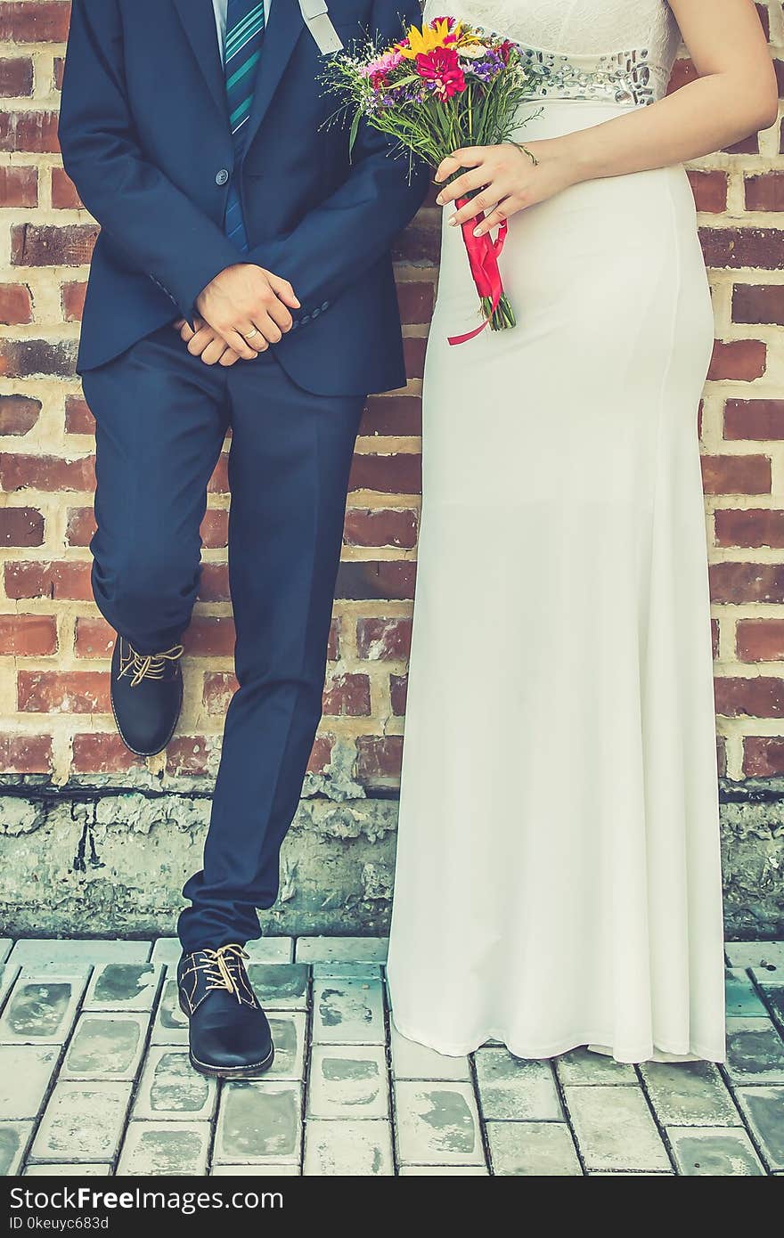 Bride and groom together in front of brick wall