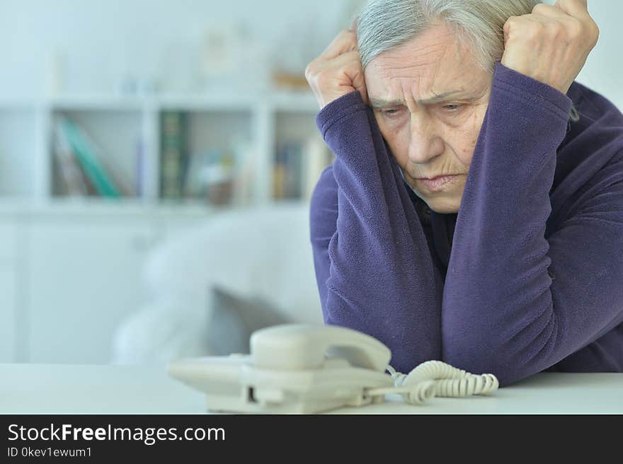 Portrait of upset senior woman with phone