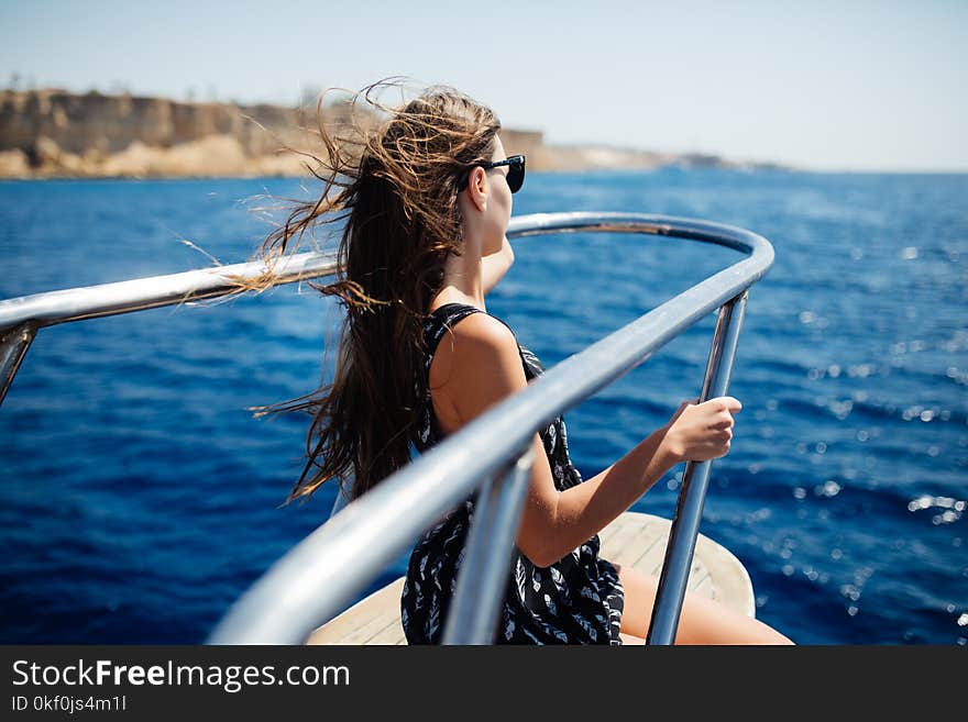 Young woman in sunglasses relax on yacht in sea. Beautiful seascape