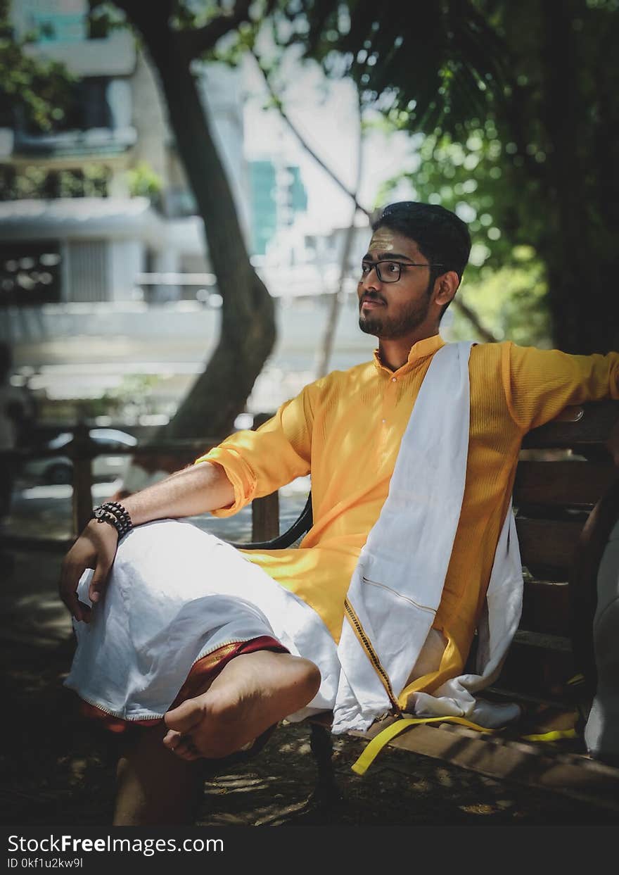 Man Wearing Yellow and White Suit Sitting on Bench