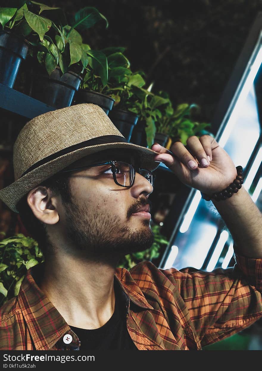 Man Wearing Brown and Gray Plaid Collared Shirt With Brown Fedora Hat and Black Framed Eyeglasses