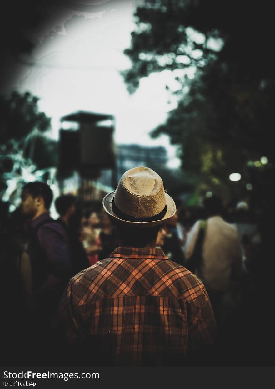 Man Wearing Fedora Hat and Plaid Shirt Facing People