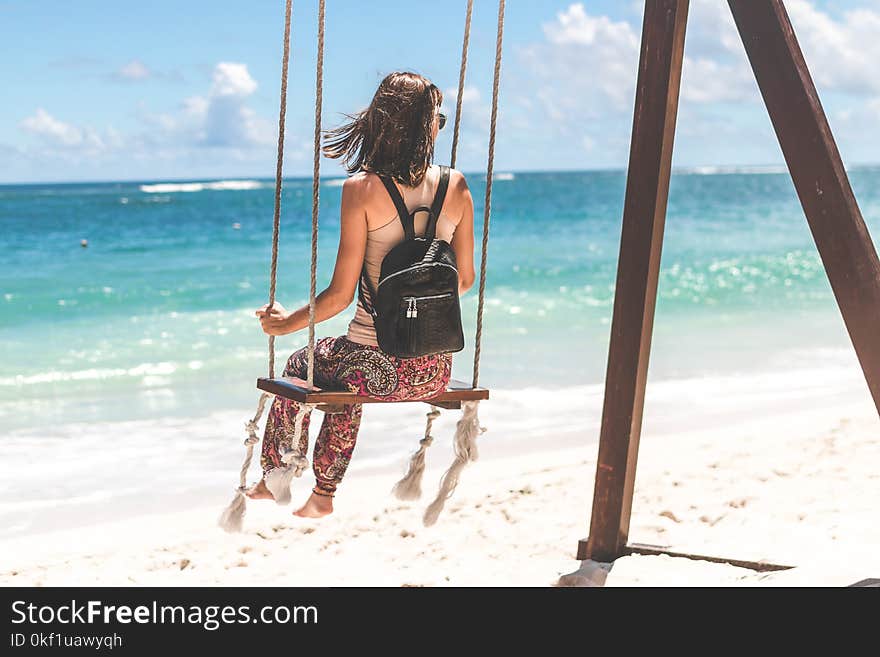 Woman Sitting on Seashore Swing