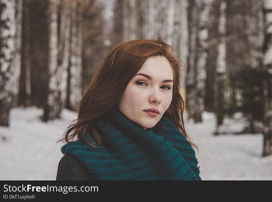 Selective Focus Photography of Woman Wearing Blue Scarf While Standing on Snow Covered Forest