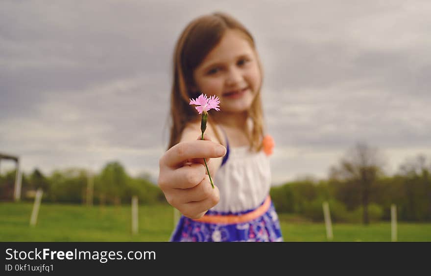 Selective Focus Photography of Girl Holding Pink Flower