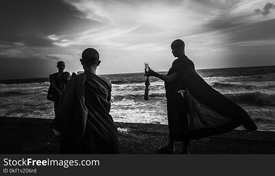 Greyscale Photography of Three Monks Near Ocean