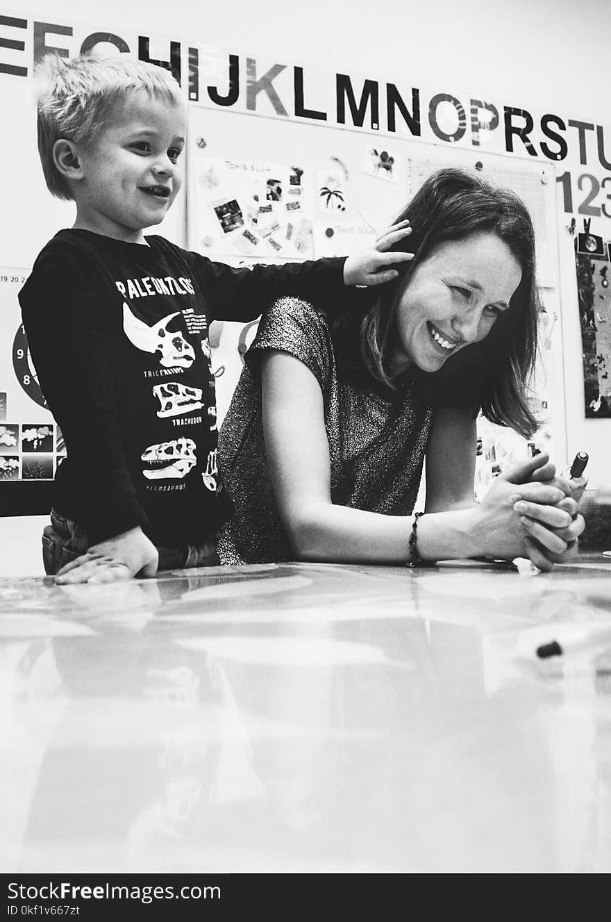 Grayscale Photography of Woman Smiling Near Kid in Black Sweater