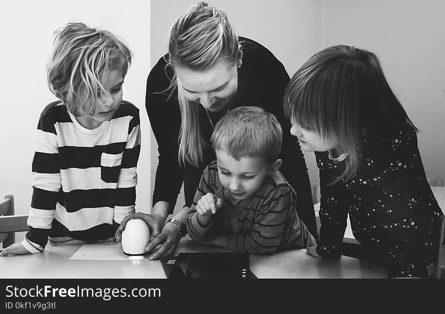 Grayscale Photo of Mother and Three Children Playing