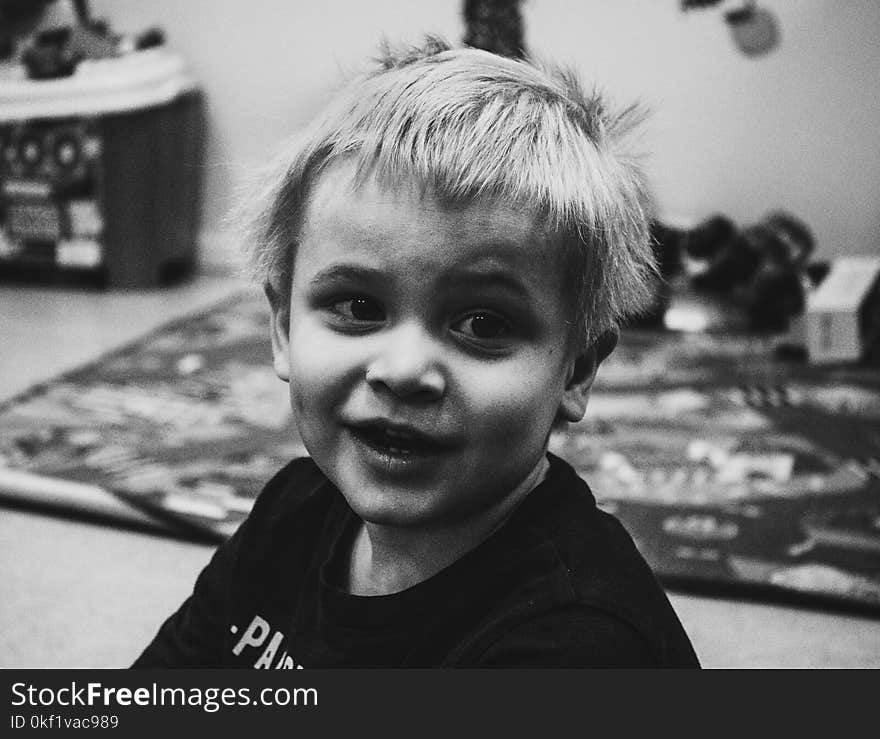 Grayscale Photo of Boy Wearing Shirt Near Storage Box Inside the Room