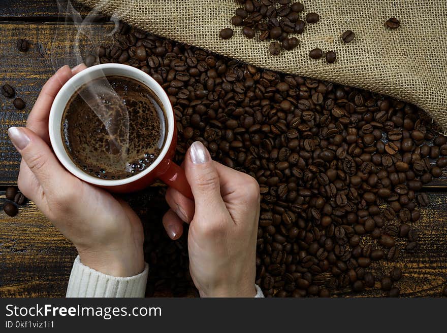 Person Holding Red Cup of Coffee Cup With Coffee Above Coffee Beans