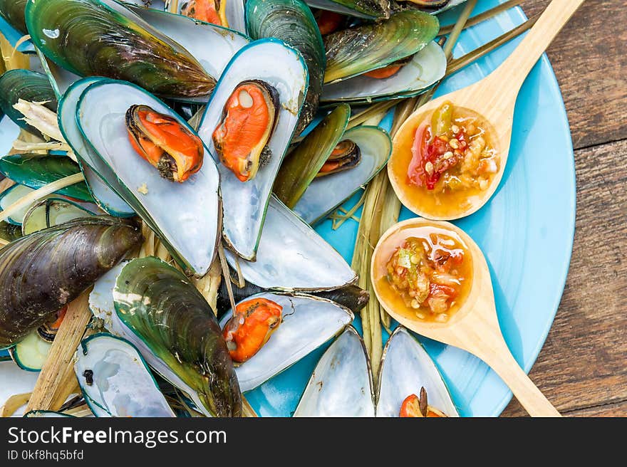 Steaming mussel With delicious sauce on dish with wood table seafood style.