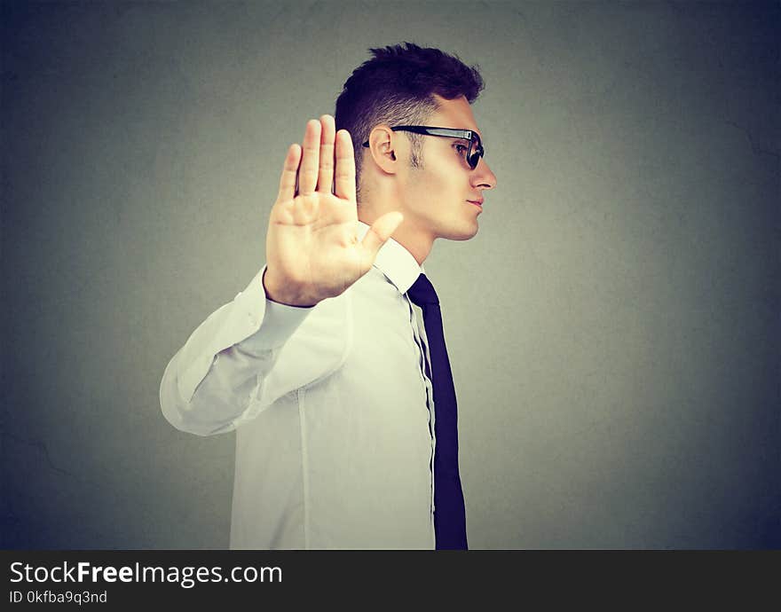 Annoyed angry man with bad attitude giving talk to hand gesture isolated on gray background.