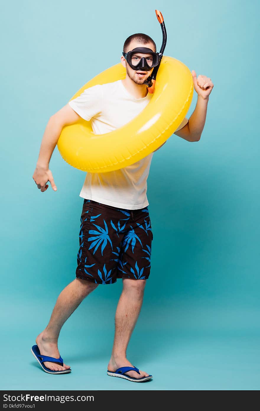 Young handsome man with inflatable yellow ring and snorkel isolated on green background. Young handsome man with inflatable yellow ring and snorkel isolated on green background