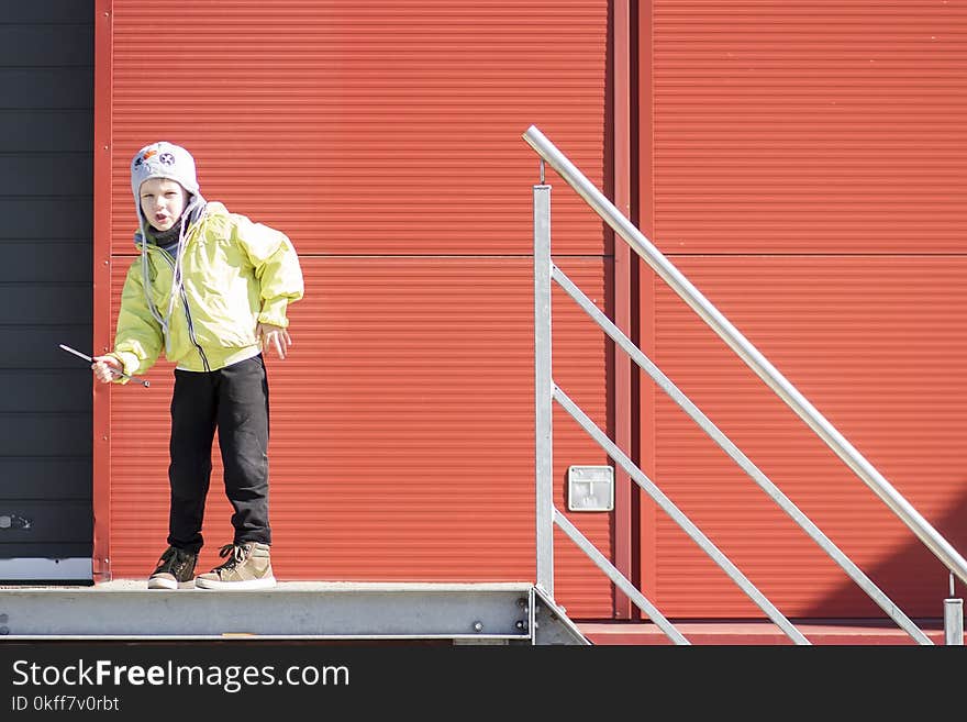 Boy moves like robot. boy plays in territory of industrial plant against background of metal profile wall. Portrait of boy