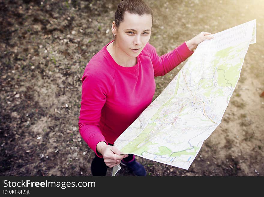 Girl with map in her hands on hike. Athlete orienteering in wild. girl is traveling with card in nature. Woman on active rest