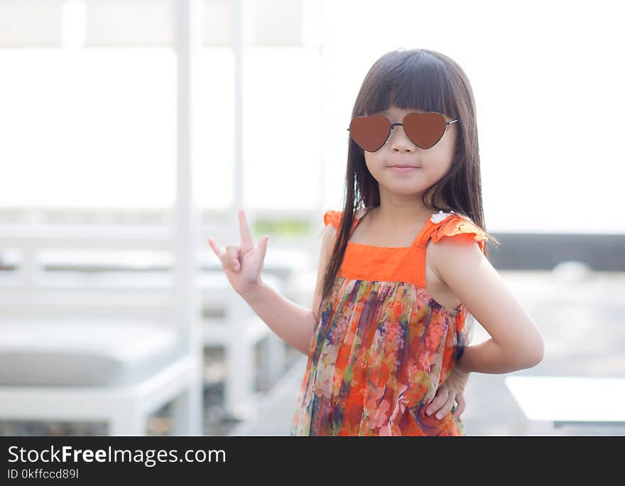 Beautiful portrait little girl asian of a smiling standing at swimming pool, kid leisure and joyful wear glasses in outdoor.