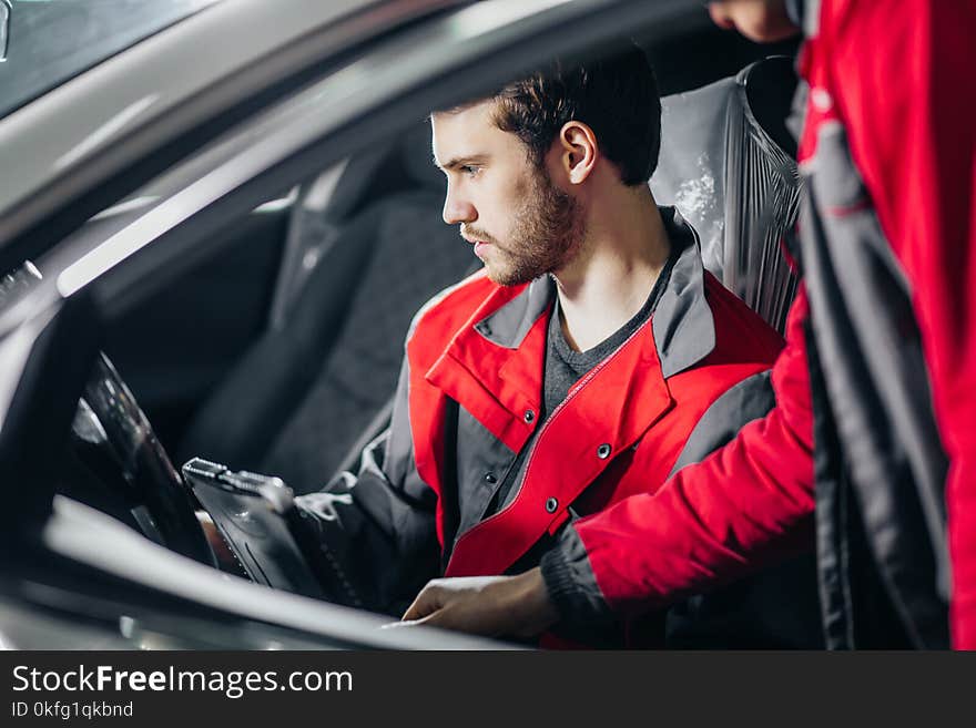 Mechanic Examining Car Engine With Help Of Laptop