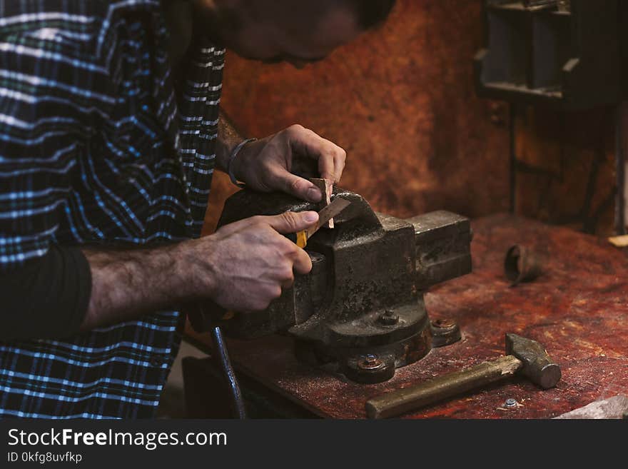 Man works in carpentry workshop. He cuts knife with wooden wedge. Different tools are on workbench. Men at work. Hand work. Man works in carpentry workshop. He cuts knife with wooden wedge. Different tools are on workbench. Men at work. Hand work.