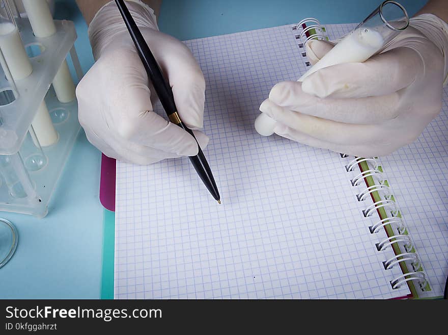 Hands in latex gloves with test tubes record in a notebook