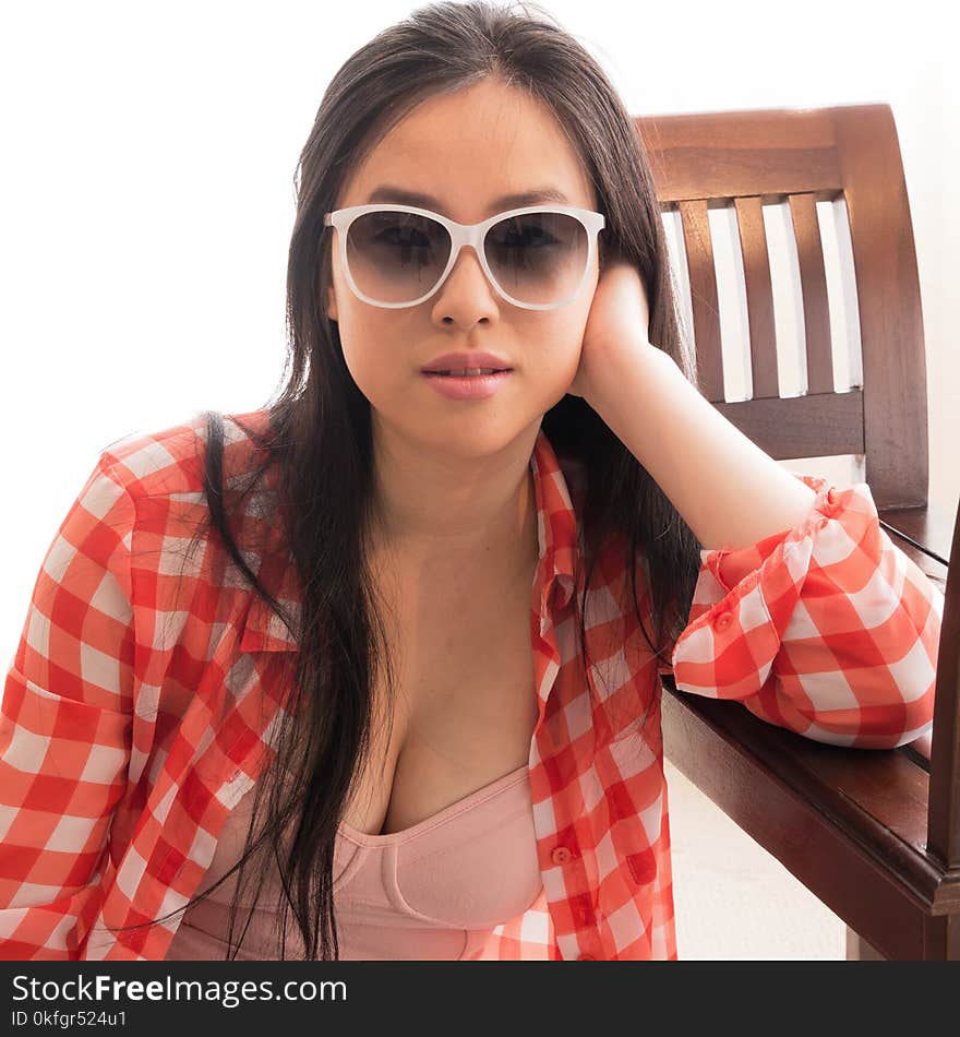 A pretty young woman poses for the camera in large sunglasses, open shirt and a low top. A pretty young woman poses for the camera in large sunglasses, open shirt and a low top