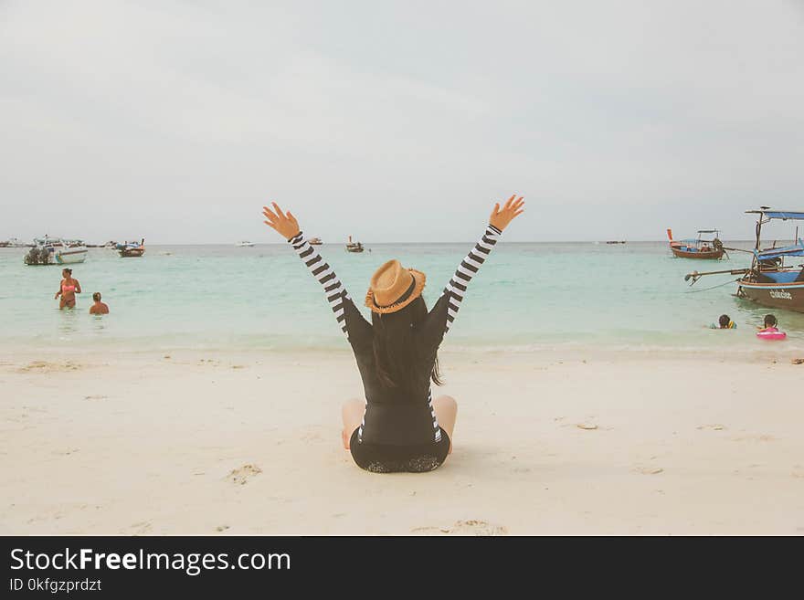 Woman Sitting at the Beach Near Boats and People during Day