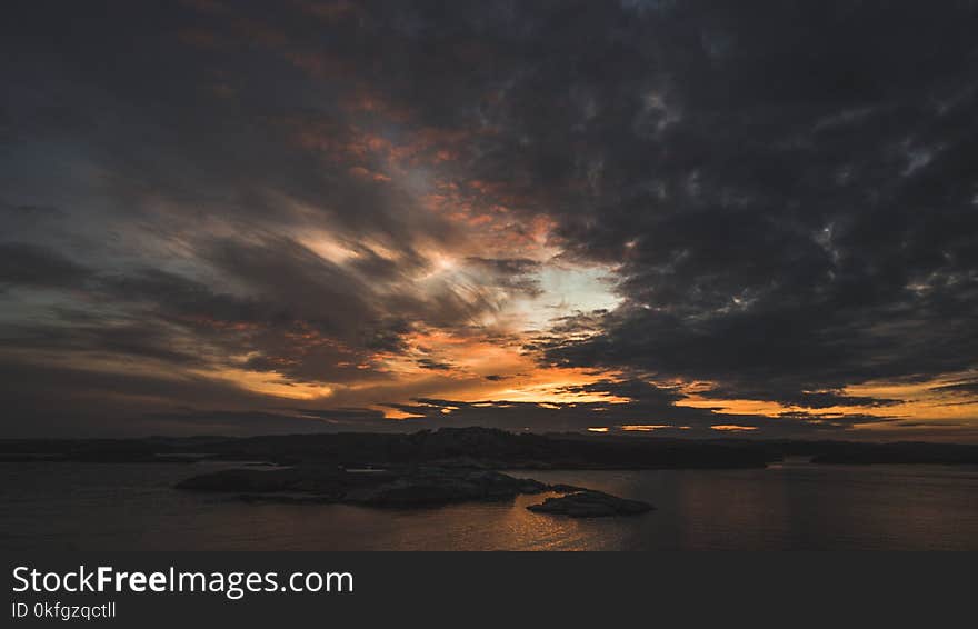 Silhouette of Island Under Grey Clouds during Golden Hour