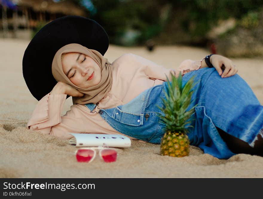 Woman in Blue Denim Dungaree Lying on Sand