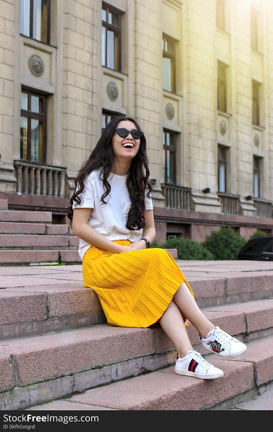 Woman Wearing White Shirt and Yellow Skirt Sitting on Brown Concrete Brick Stairs