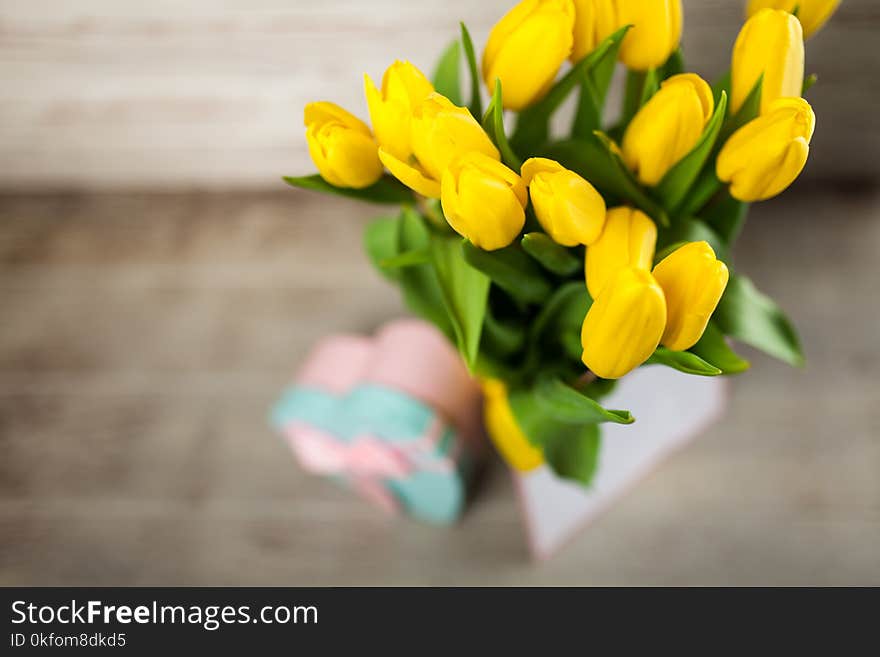 Yellow tulips in a vase on white wood background. Yellow tulips in a vase on white wood background