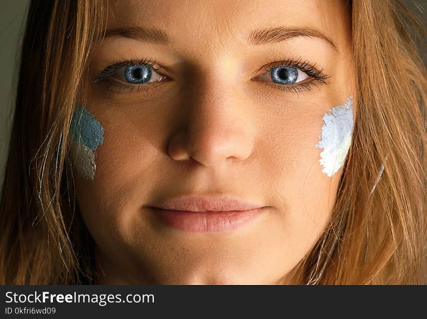 Portrait of a woman with the flag of the Argentina painted on her face.