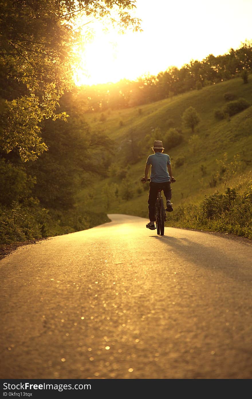 Teenager riding a bicycle on the road summer sunlit